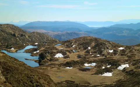 Vacker utsikt över Ulriken i Bergen med små sjöar och snöfläckar på bergssluttningarna.