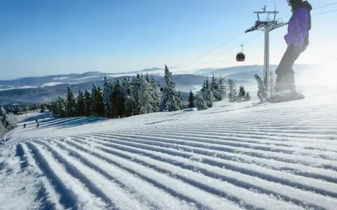 Perfekt preparerad pist för sommarskidåkning i Norge. En snowboardåkare och en skidåkare njuter av den soliga dagen.