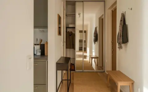 Liten hall inspiration med skjutdörrsgarderob i spegelglas, en smal konsol och en bänk i trä.