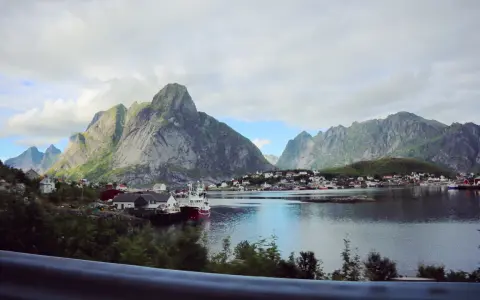 Vacker vy över en by vid vattnet, omgiven av dramatiska berg. Kanske en vy från Narvik mot Lofoten?