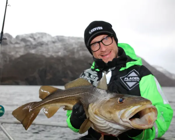 Glad fiskare visar upp en stor torsk fångad i Norge.