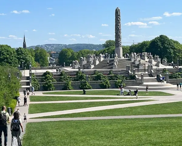 Vigelandsparken med dess imponerande monoliten och skulpturer, en solig dag med besökare som njuter av parken.