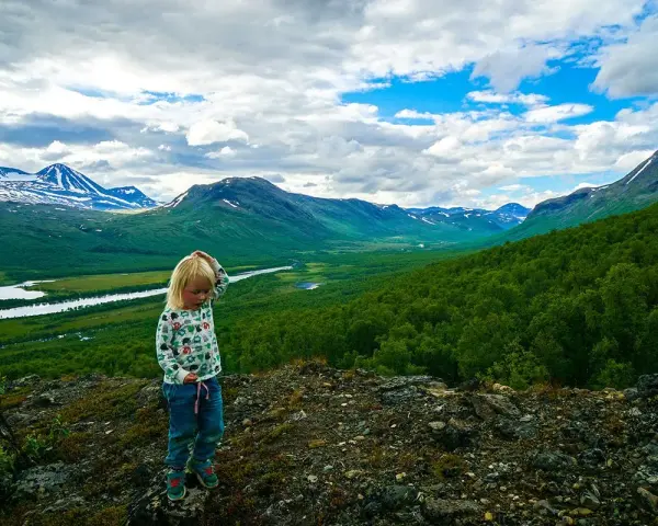 Ett barn funderar på den storslagna utsikten under en vandring med barn i fjällen.