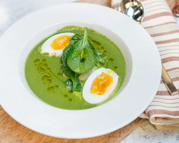 Grön spenatsoppa med halverat kokt ägg och färska spenatblad. Ett enkelt och gott spenatsoppa recept.