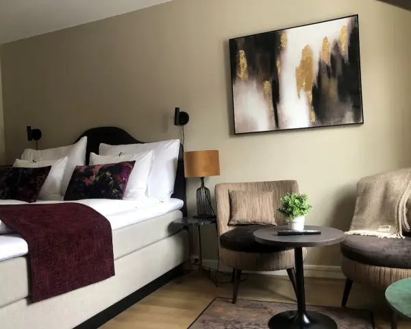 Mysigt hotellrum inredning med stor säng, bekväma fåtöljer och modern konst.