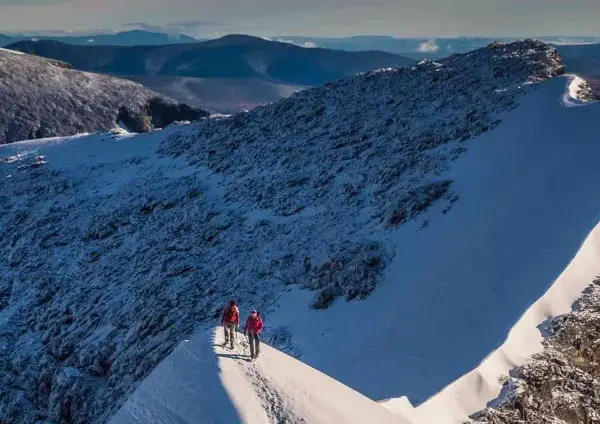 Två vandrare på en snöig bergskam, redo att bestiga Kebnekaise. Vacker utsikt över fjällen.