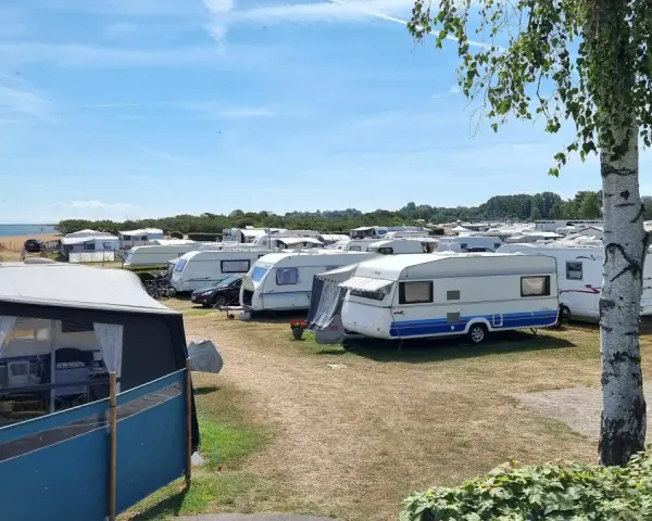 En stor campingplats med många husvagnar. Solen skiner och himlen är blå.