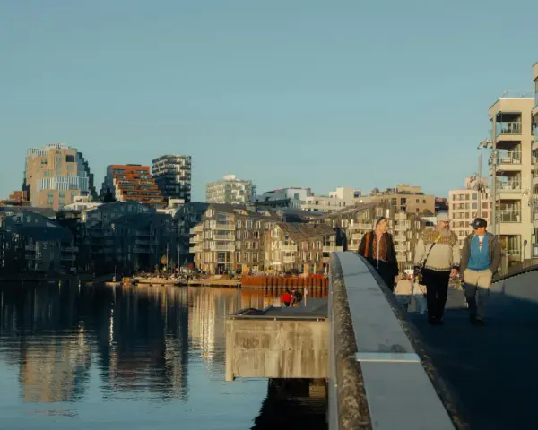 Promenad över bron i Oslo centrum med moderna byggnader och vatten.