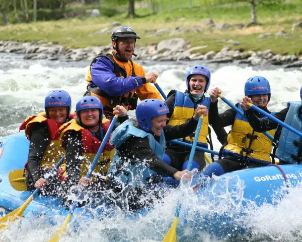 Glada människor i en flotte på forsigtigt vatten, redo för sjoa rafting.