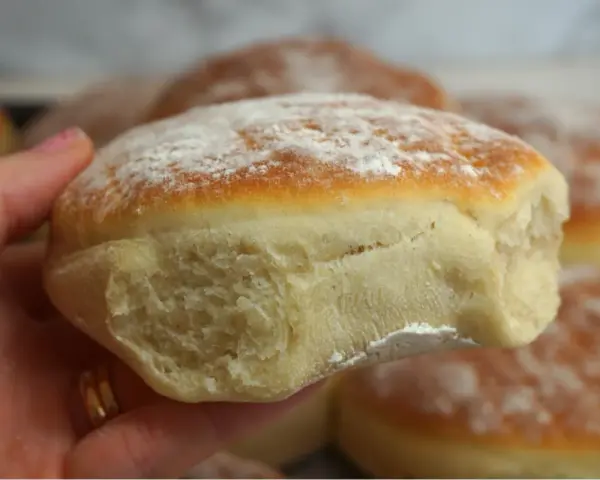 En hand håller en nybakad tekaka, pudrad med mjöl. Perfekt för ett enkelt tekakor recept.