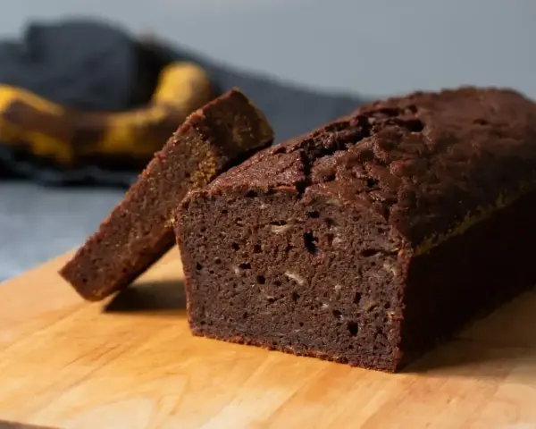 En saftig banankaka utan socker, perfekt för en hälsosam fika. En skiva är uppskuren och en banan syns i bakgrunden.