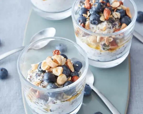 Två glas med overnight oats, toppade med blåbär, nötter och honung. Perfekt frukost!