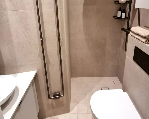 Modernt och stilrent små badrum inspiration med dusch, handfat och vägghängd toalett. Ljusbeige kakel ger en lugn känsla.
