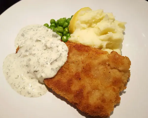 Panerad fisk med potatismos, ärtor och en krämig skolans fisksås.