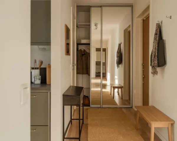Liten hall inspiration med skjutdörrsgarderob i spegelglas, en smal konsol och en bänk i trä.