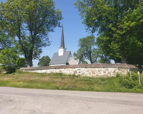 Kyrka med spira bakom stenmur och träd. En skylt visar "2 St". Kanske en vy från Hamar, Norge.