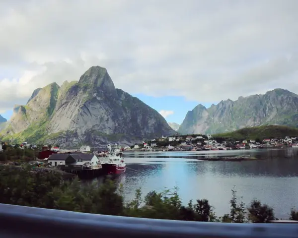 Vacker vy över en by vid vattnet, omgiven av dramatiska berg. Kanske en vy från Narvik mot Lofoten?