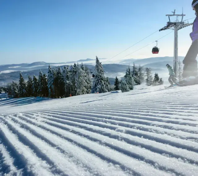 Perfekt preparerad pist för sommarskidåkning i Norge. En snowboardåkare och en skidåkare njuter av den soliga dagen.