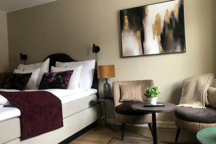 Mysigt hotellrum inredning med stor säng, bekväma fåtöljer och modern konst.