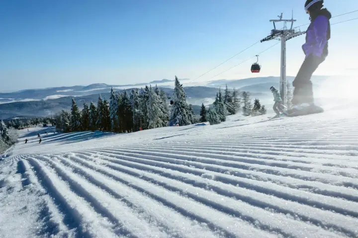 Perfekt preparerad pist för sommarskidåkning i Norge. En snowboardåkare och en skidåkare njuter av den soliga dagen.