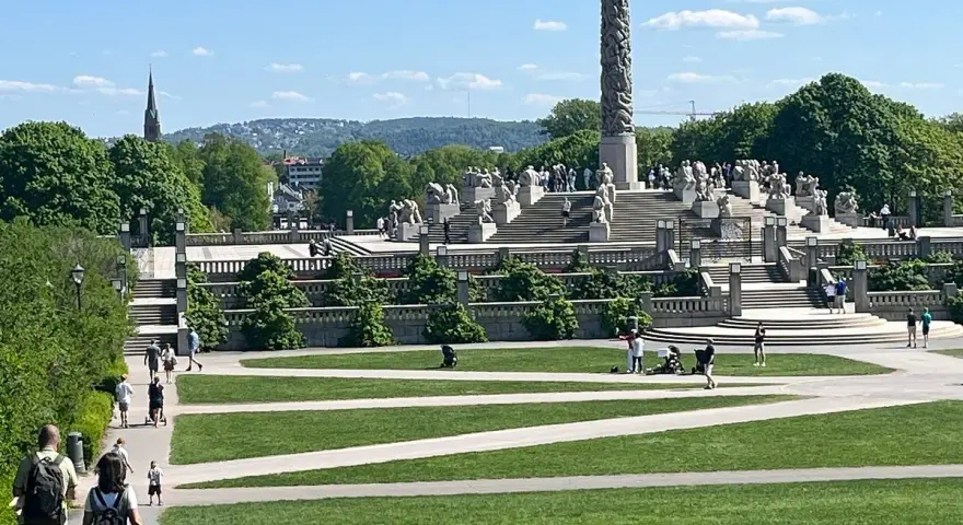 Vigelandsparken med dess imponerande monoliten och skulpturer, en solig dag med besökare som njuter av parken.