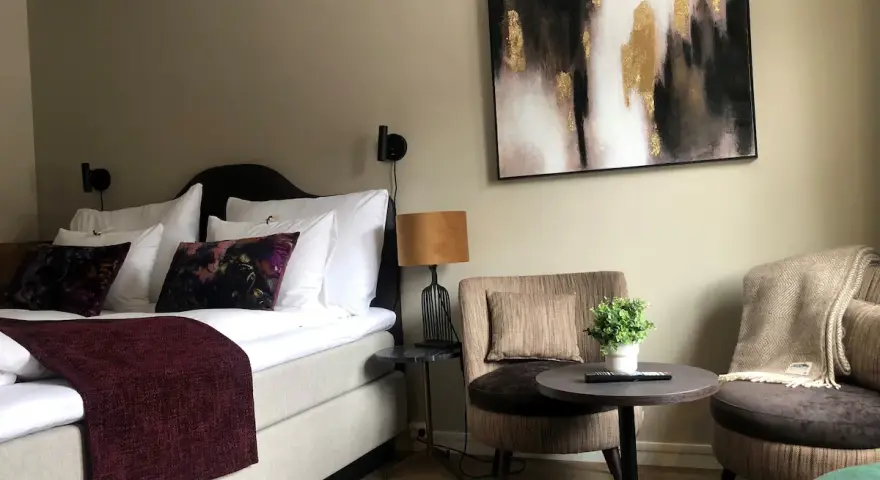 Mysigt hotellrum inredning med stor säng, bekväma fåtöljer och modern konst.