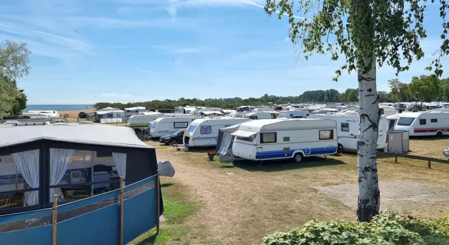 En stor campingplats med många husvagnar. Solen skiner och himlen är blå.