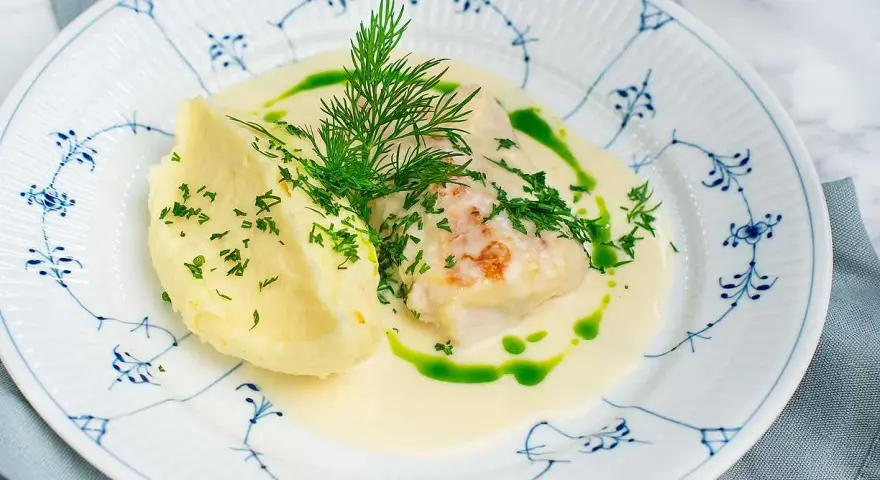 En vacker tallrik med torsk i en krämig sås, serverad med potatismos och dill. Ett perfekt torsk recept för en festmåltid.