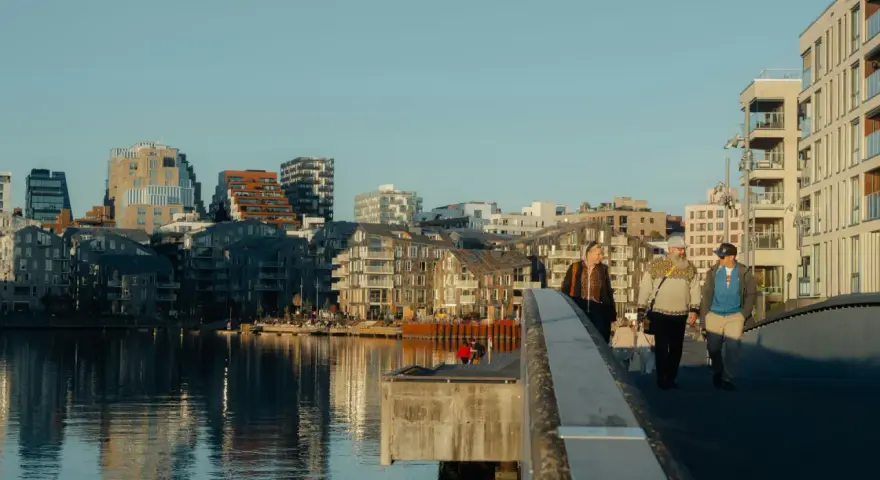 Promenad över bron i Oslo centrum med moderna byggnader och vatten.