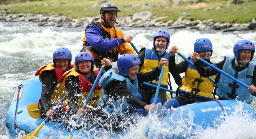 Glada människor i en flotte på forsigtigt vatten, redo för sjoa rafting.