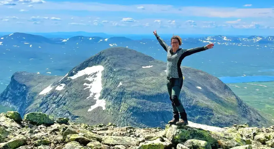 Lycklig vandrare på en bergstopp med vidsträckt utsikt över fjällandskap. Här finns fina vandringsleder för alla.