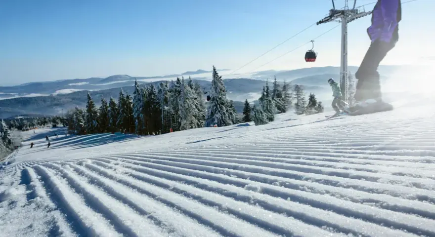 Perfekt preparerad pist för sommarskidåkning i Norge. En snowboardåkare och en skidåkare njuter av den soliga dagen.