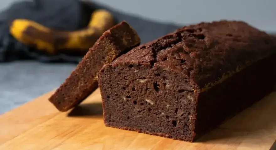 En saftig banankaka utan socker, perfekt för en hälsosam fika. En skiva är uppskuren och en banan syns i bakgrunden.