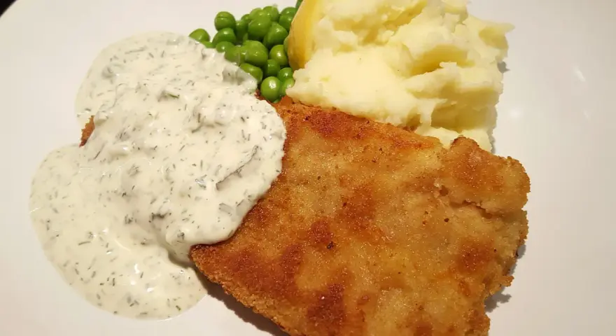 Panerad fisk med potatismos, ärtor och en krämig skolans fisksås.