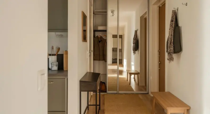 Liten hall inspiration med skjutdörrsgarderob i spegelglas, en smal konsol och en bänk i trä.