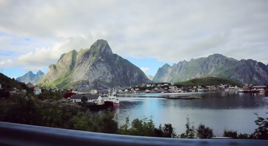 Vacker vy över en by vid vattnet, omgiven av dramatiska berg. Kanske en vy från Narvik mot Lofoten?