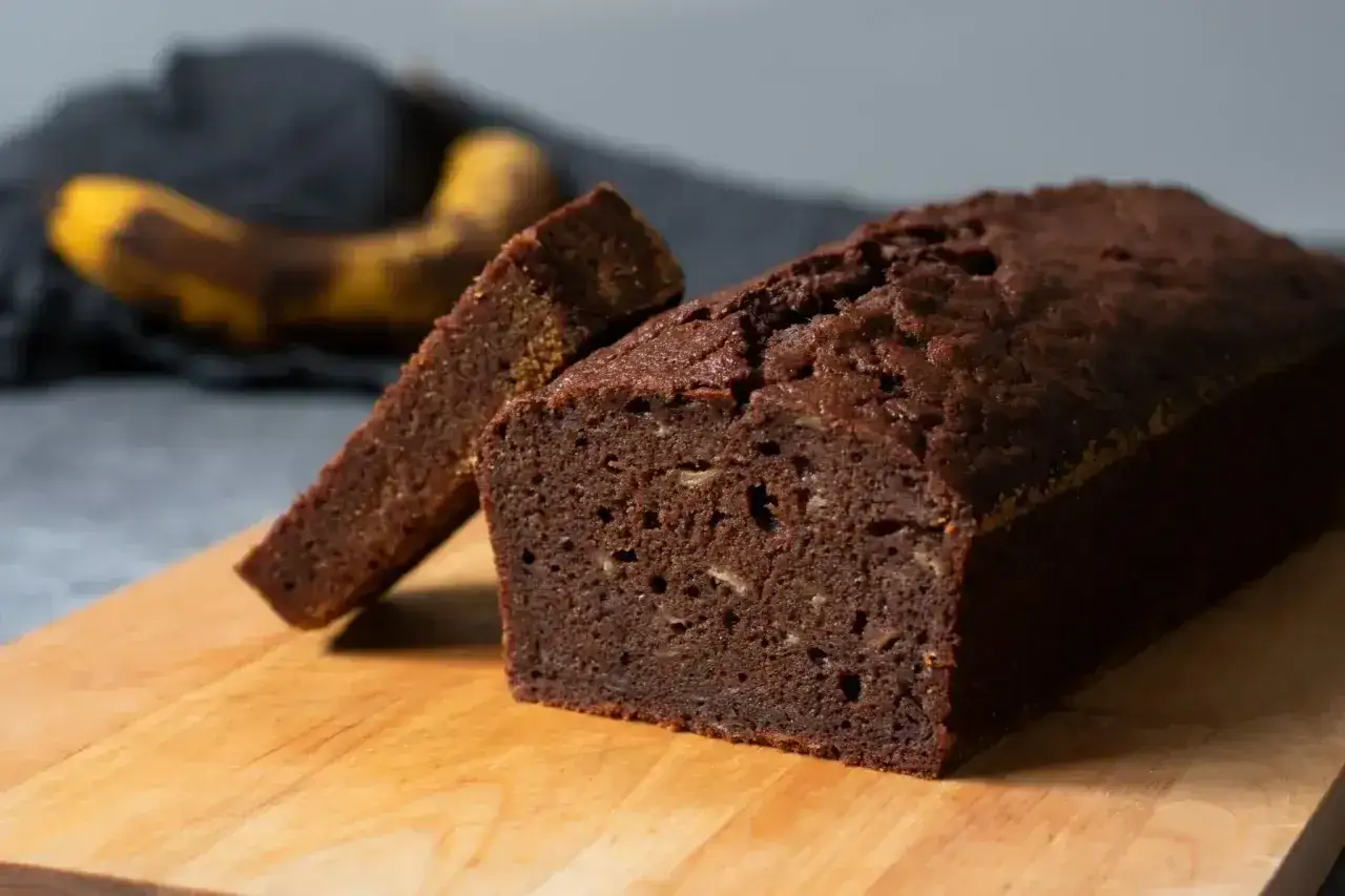En saftig banankaka utan socker, perfekt för en hälsosam fika. En skiva är uppskuren och en banan syns i bakgrunden.