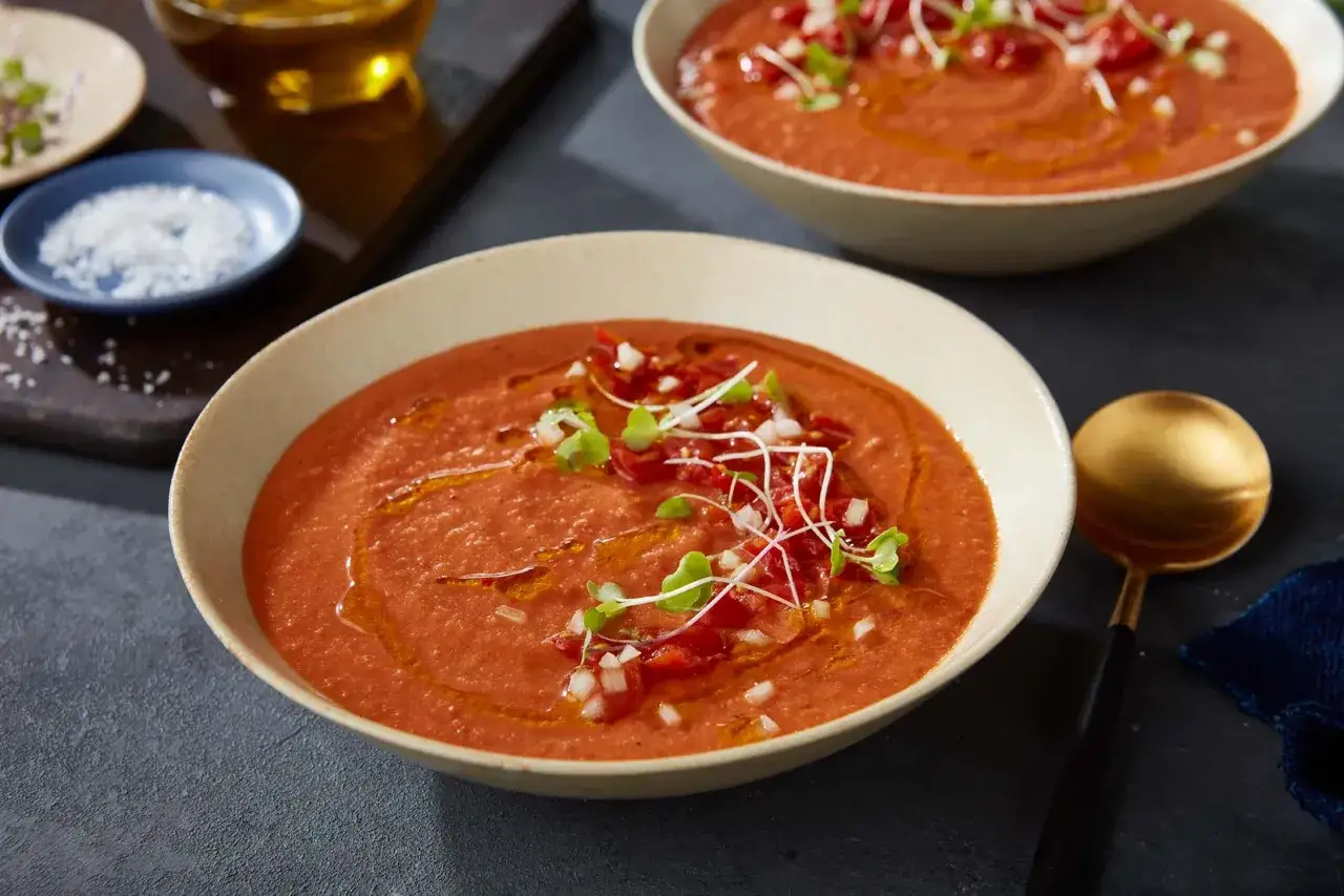 En sk&aring;l med kr&auml;mig tomatsoppa, perfekt f&ouml;r ett enkelt tomatsoppa recept. Garnerad med t&auml;rnad tomat, l&ouml;k och groddar.