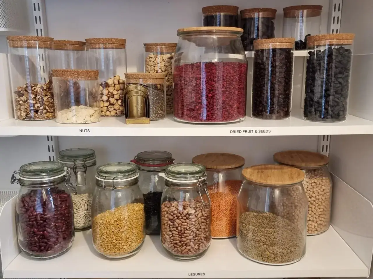 Fina glasburkar med korklock för att organisera skafferi. Nötter, torkad frukt, frön och baljväxter prydligt uppradade.
