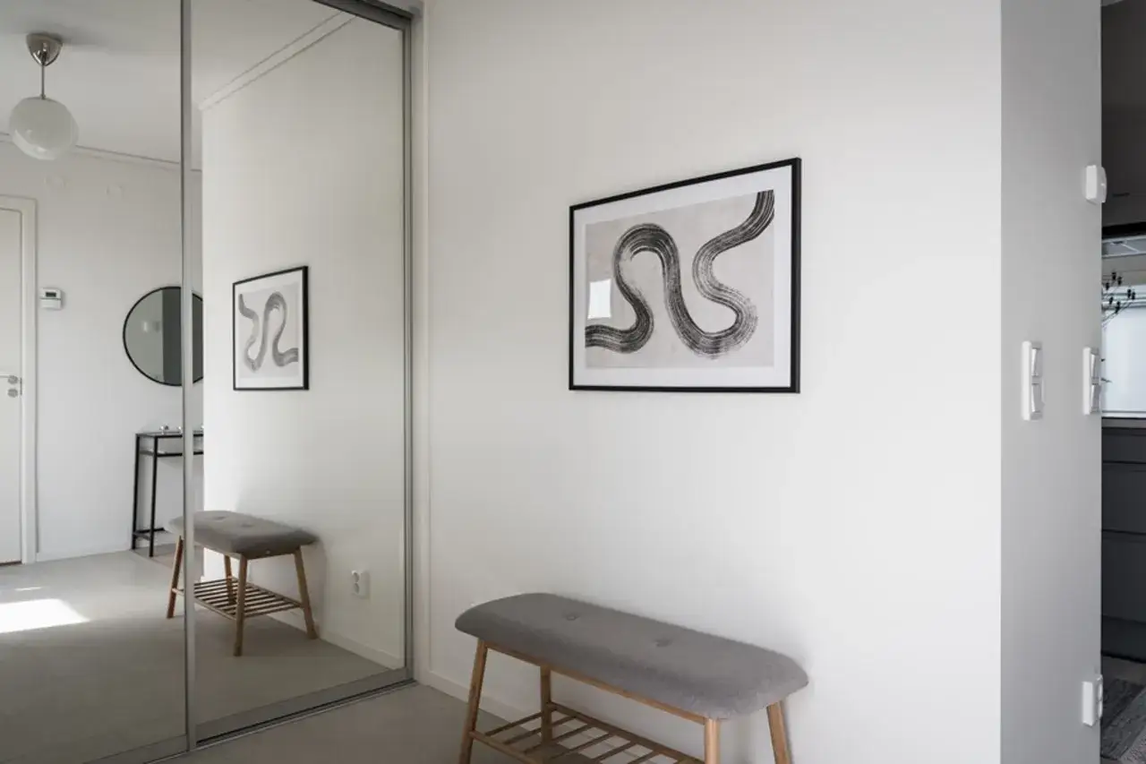 Snygga inredningstips hall: en grå sittbänk framför en stor spegel med en abstrakt tavla ovanför.