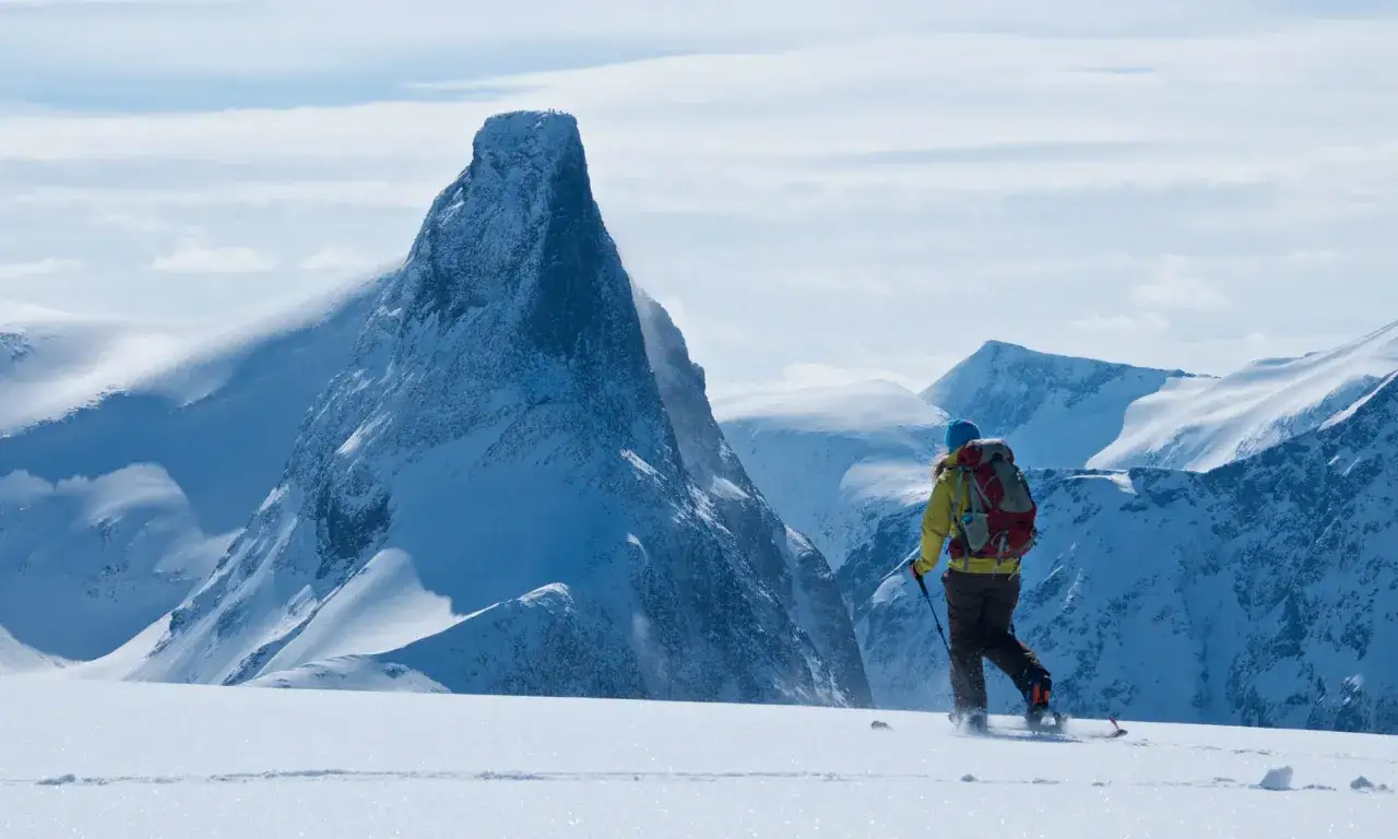 En person på skidor i Norge närmar sig ett dramatiskt snöklätt berg.