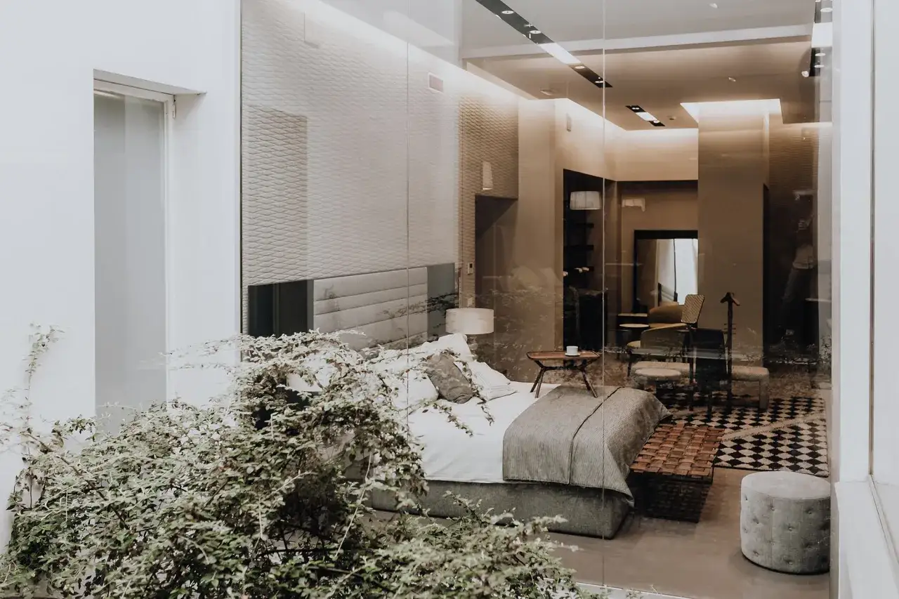 Sovrum med en stor säng, en sittgrupp och en spegel. En grönskande växt ramar in rummet, vilket skapar en känsla av lugn och harmoni, typisk för feng shui inredning.