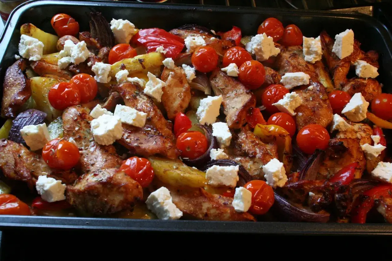 En h&auml;rlig grekisk pyttipanna med kyckling, potatis, tomater, paprika och fetaost i en ugnsform.