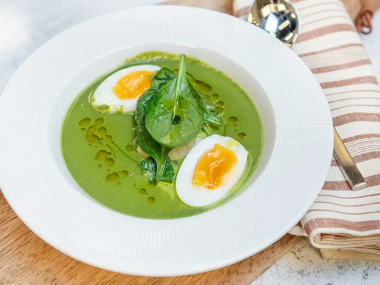 Krämig spenatsoppa med halverat kokt ägg och färska spenatblad. Ett perfekt spenatsoppa recept för en snabb och näringsrik måltid.