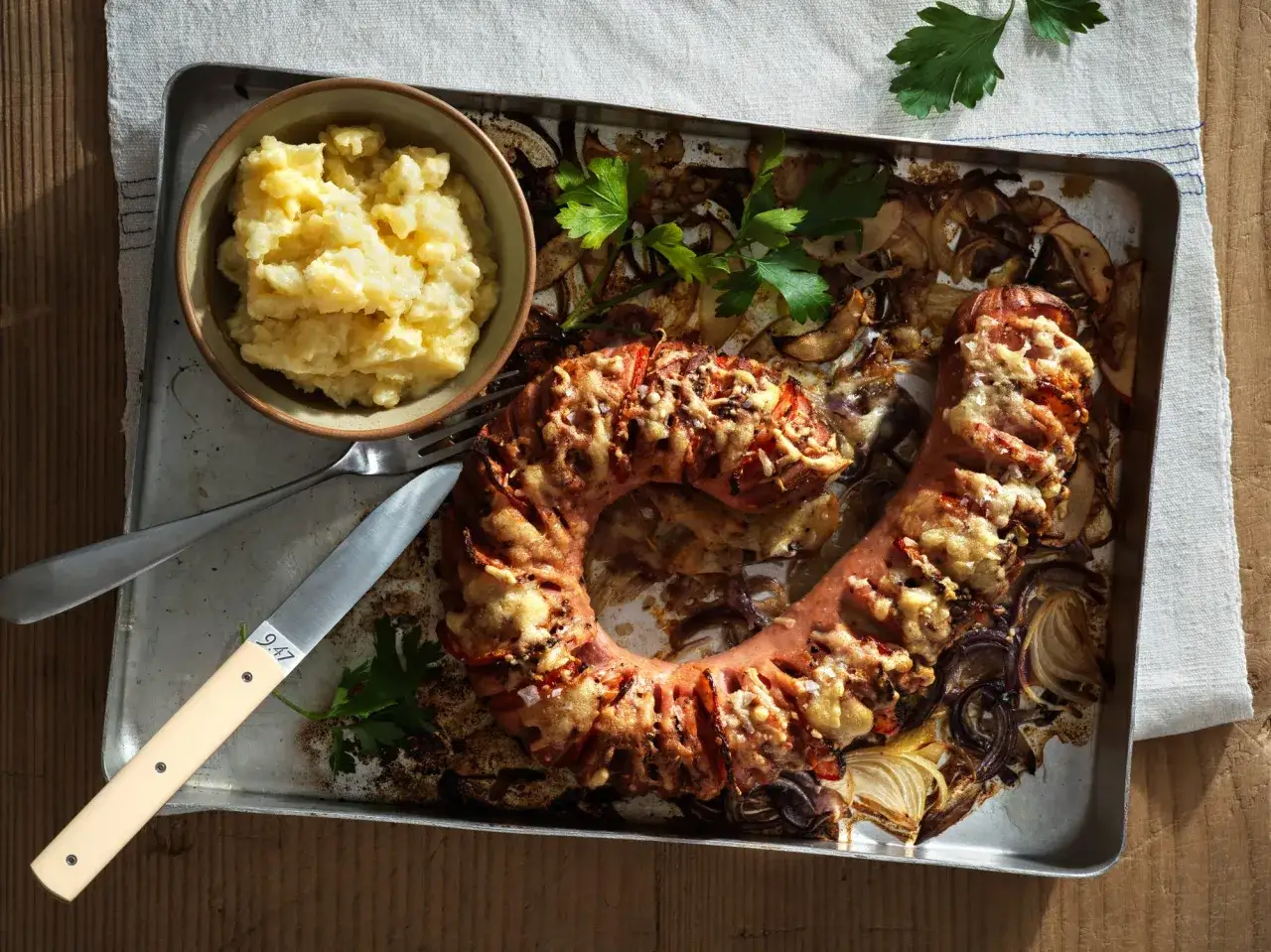 En ring av falukorv i ugn, gratinerad med ost och serverad med potatismos.