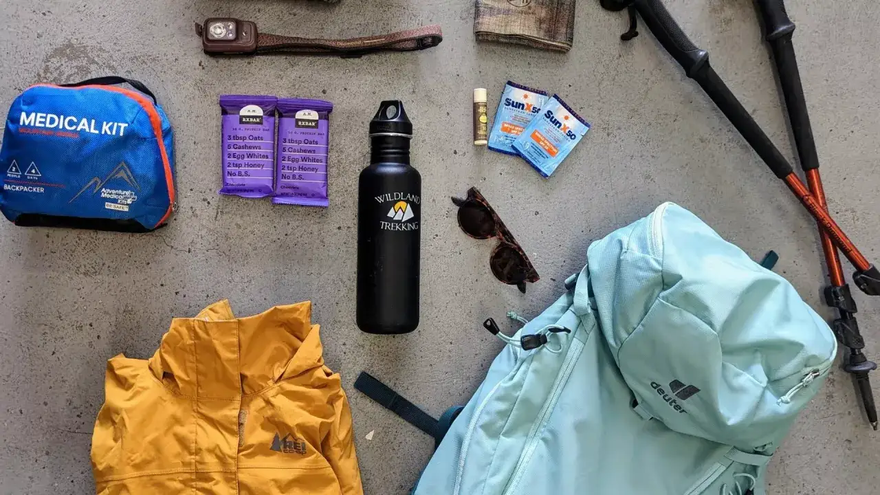 Packlista vandring – dagstur: ryggsäck, jacka, vattenflaska, första hjälpen, solskydd, solglasögon, pannlampa och vandringsstavar.