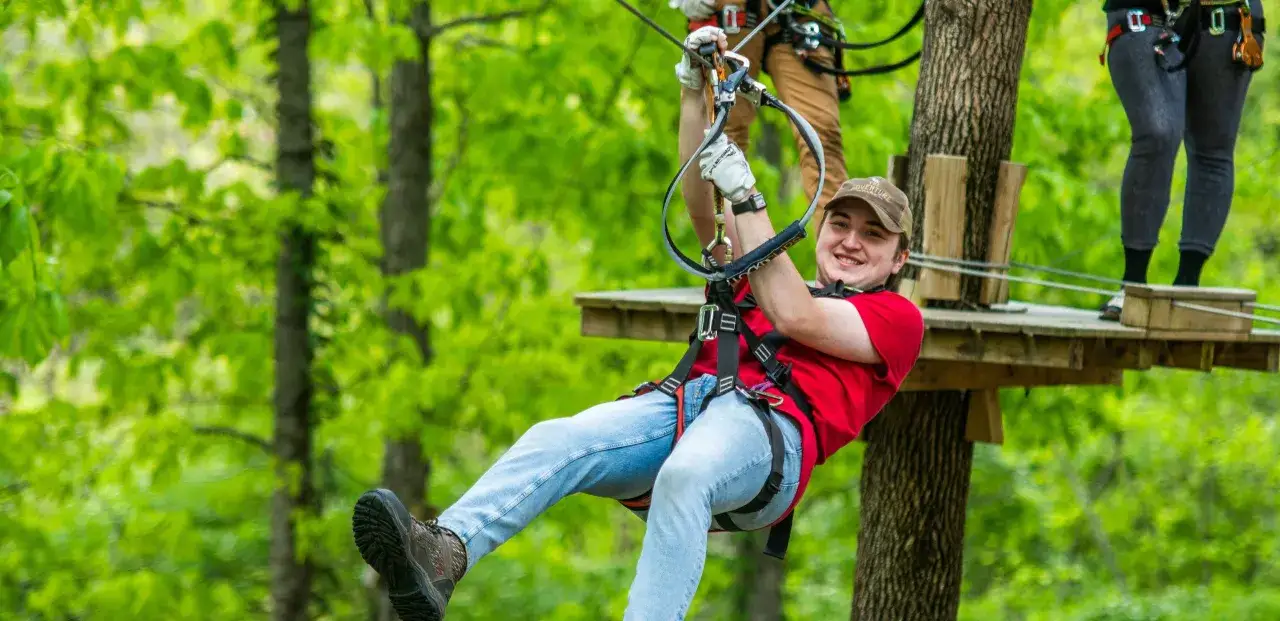 En glad kille susar genom träden på rypetoppen adventurepark.