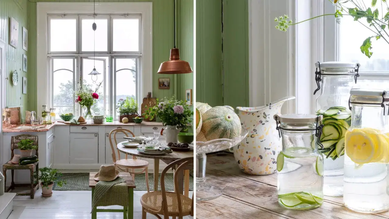 Ljust kök med allmoge inredning, koppar, blommor och frukt. Vattenkaraffer med citron och gurka på träbord.