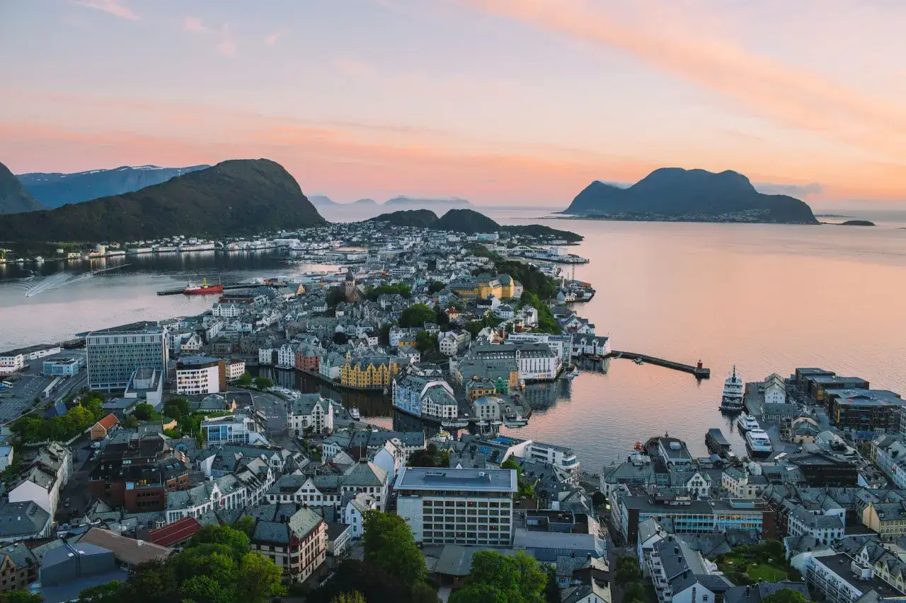 Vacker solnedg&aring;ng &ouml;ver &Aring;lesund, Norge, med sina f&auml;rgglada hus och omgivande berg.
