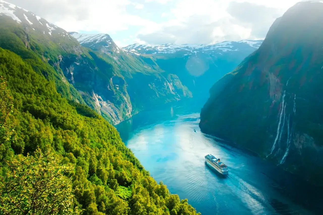 Kryssningsfartyg i en fjord med gröna berg och vattenfall. En av de fina platserna i Norge.